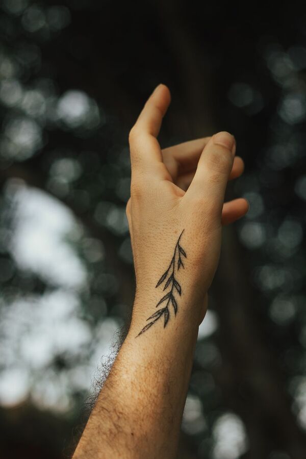Raised hand with a small plant sprig tattoo on the wrist