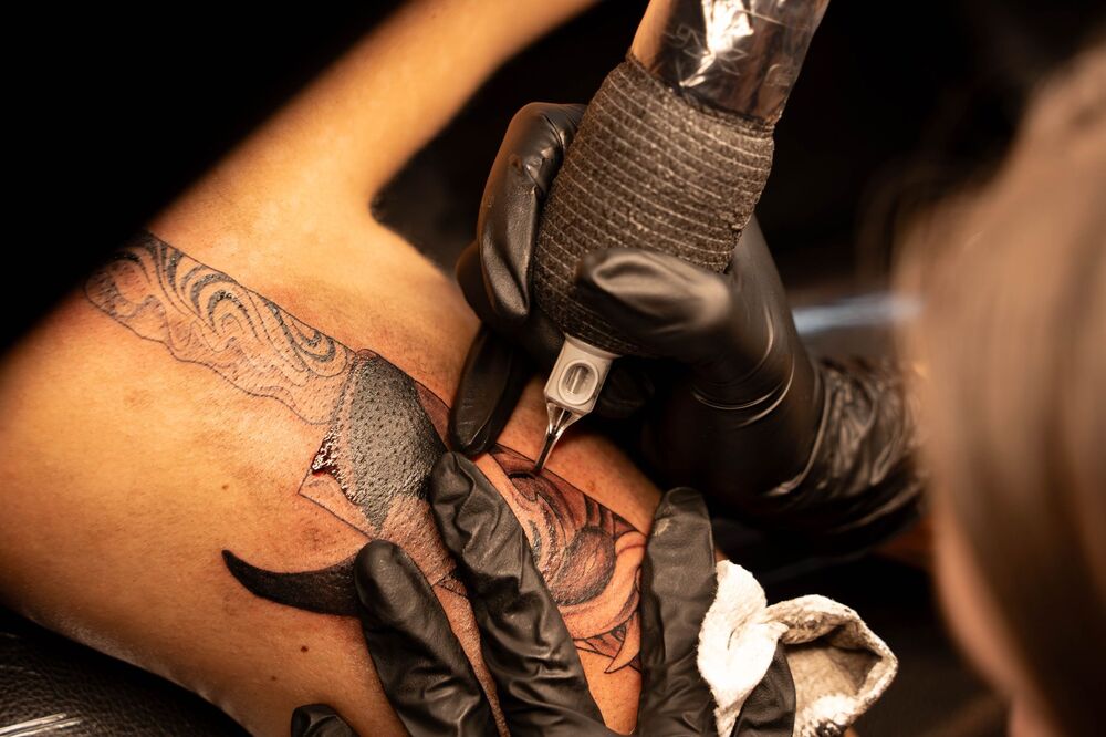 Tattoo artist working on a detailed black and grey design
