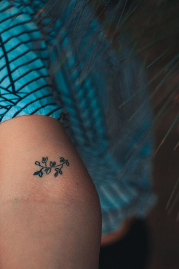 Small delicate flower tattoo on the back of the arm