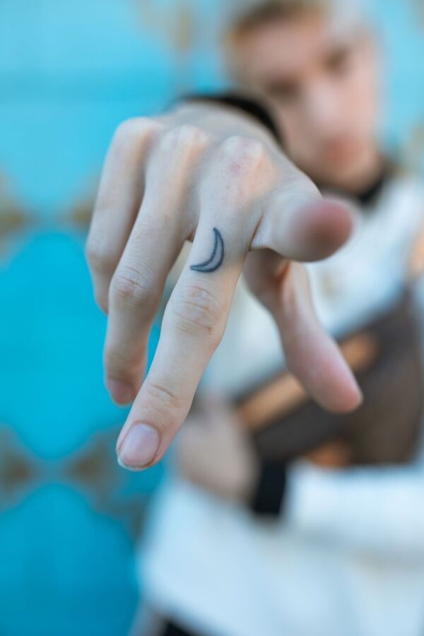 Finger with a small crescent moon tattoo