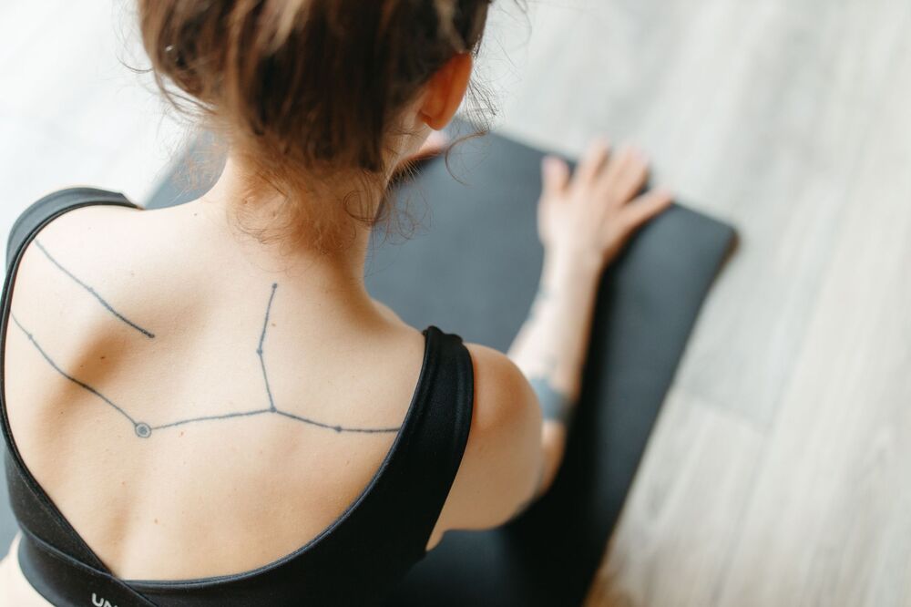 Woman with a fine line constellation tattoo across her upper back