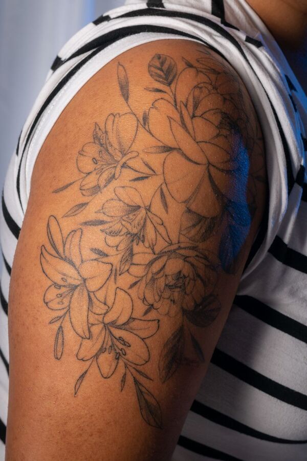 Fine line floral tattoo covering the upper arm and shoulder