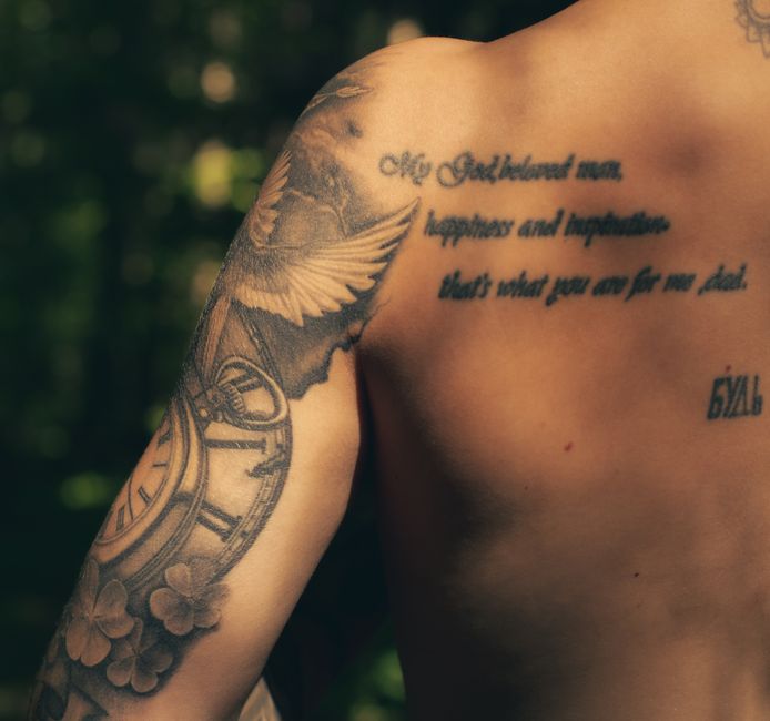 A captivating close-up of a tattooed arm showcasing artistic designs and motivational text.
