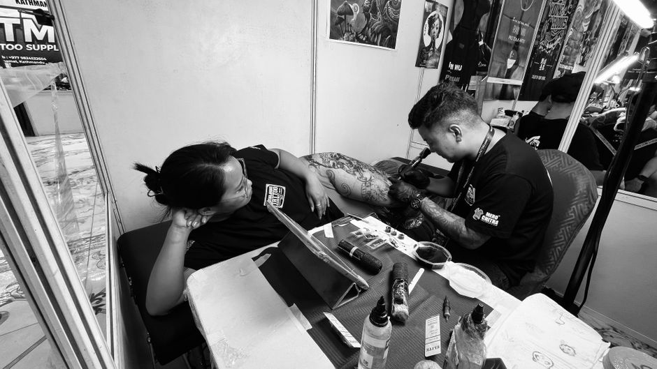 Tattoo artist ink woman in casual tattoo studio setting.