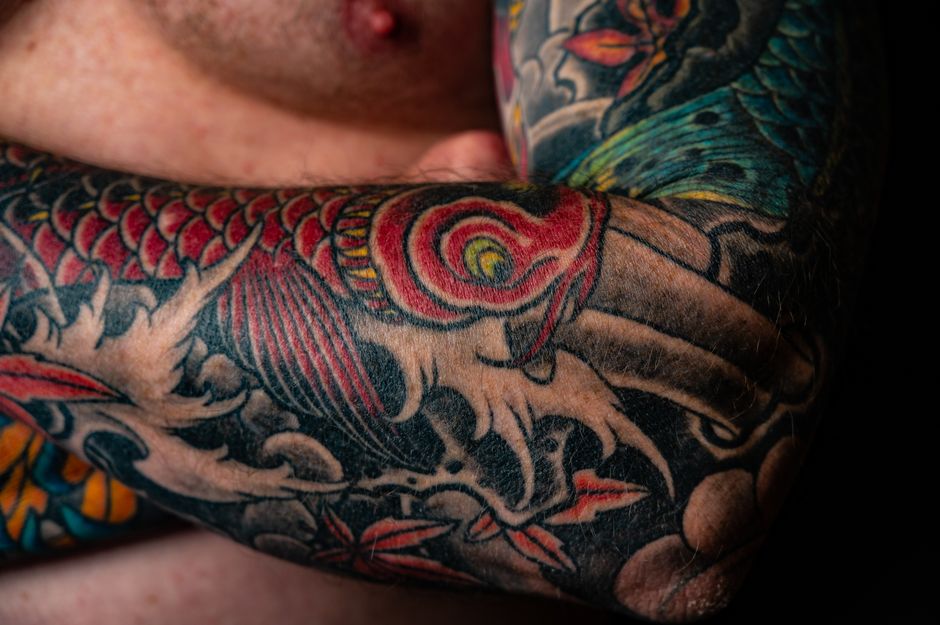 Colourful Japanese style tattoo sleeve with a koi and waves on a man's arm