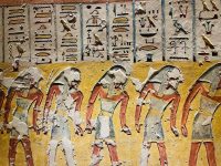 Ancient Egyptian tomb painting with hieroglyphics above a procession of figures