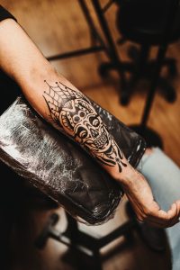 Tatuaje ornamental de calavera recién hecho en el antebrazo de un hombre