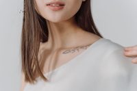 Woman with a delicate fine line floral tattoo on her collarbone