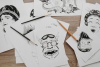 Traditional tattoo flash drawings spread on a table with pencils