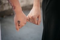 Pareja con tatuajes en las manos entrelazando los dedos meñiques