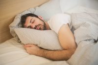 Man sleeping peacefully on clean striped bedding