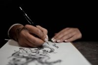Tattoo artist sketching a dragon design with a pencil on white paper
