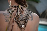 Woman's upper back with a cherub tattoo and fine line ornamental tattoos under a tied silk scarf