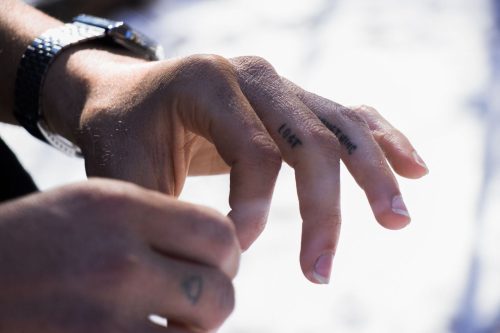 Mano de hombre con pequeños tatuajes en los dedos a la luz natural