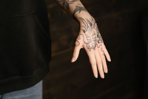 Mano con un tatuaje de dragón en tinta negra con gran detalle