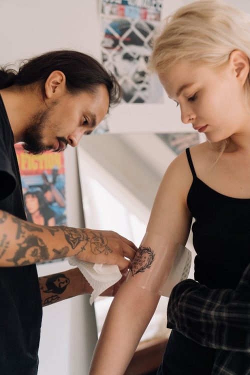 Tatuador envolviendo con film un tatuaje recién hecho para que empiece a curar