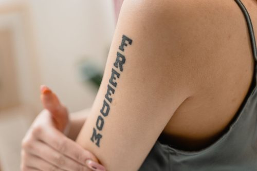 Brazo de una mujer con la palabra Freedom tatuada en letras verticales